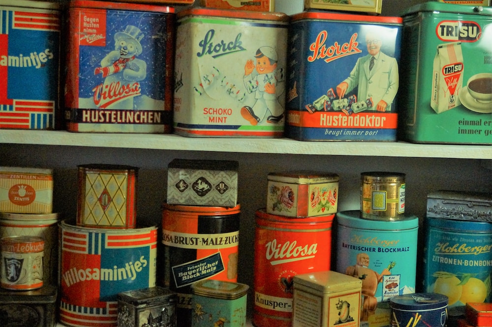 assorted cans on brown wooden shelf
